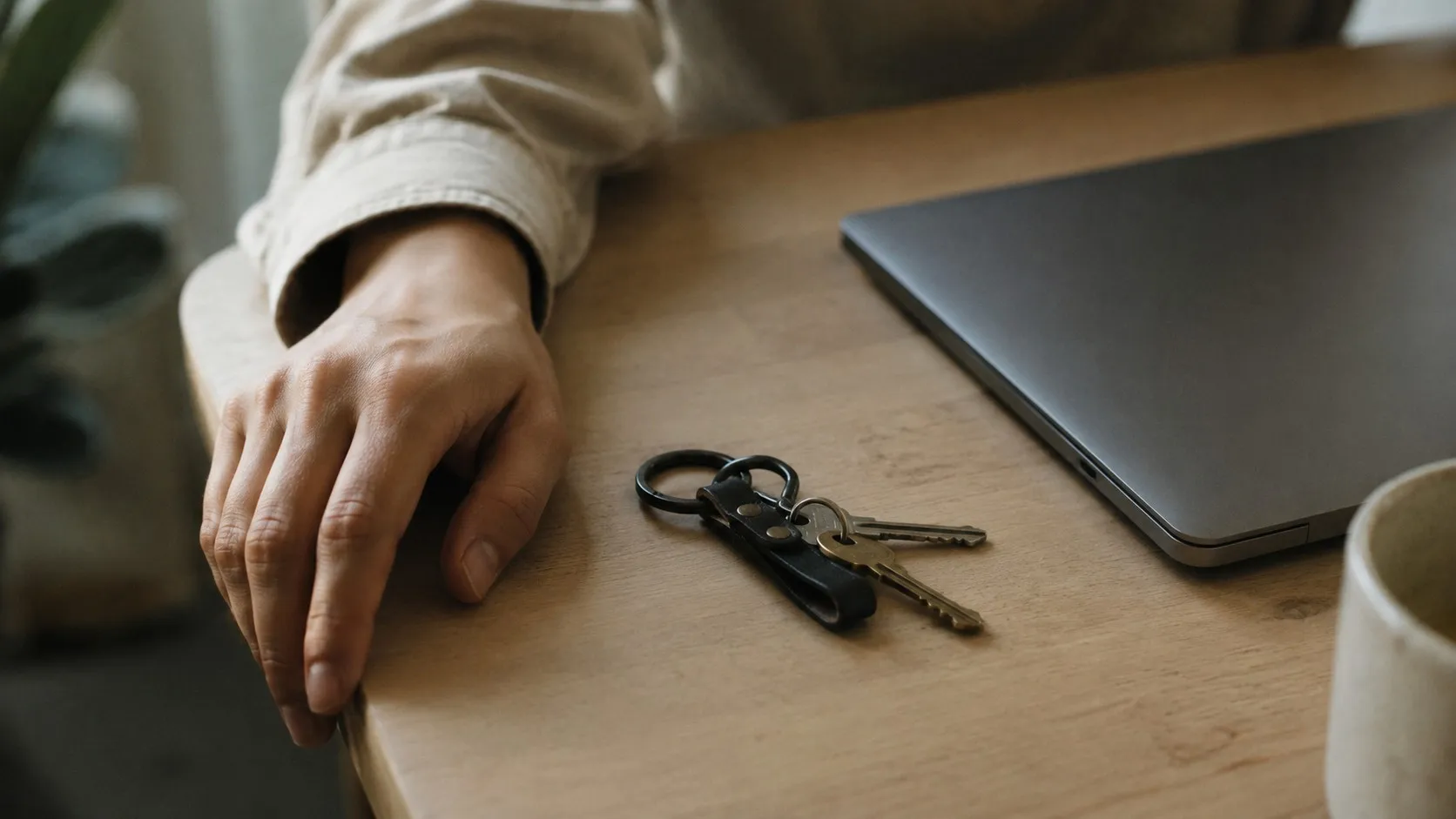 En nyckelknippa ligger på ett skrivbord bredvid en stängd laptop
